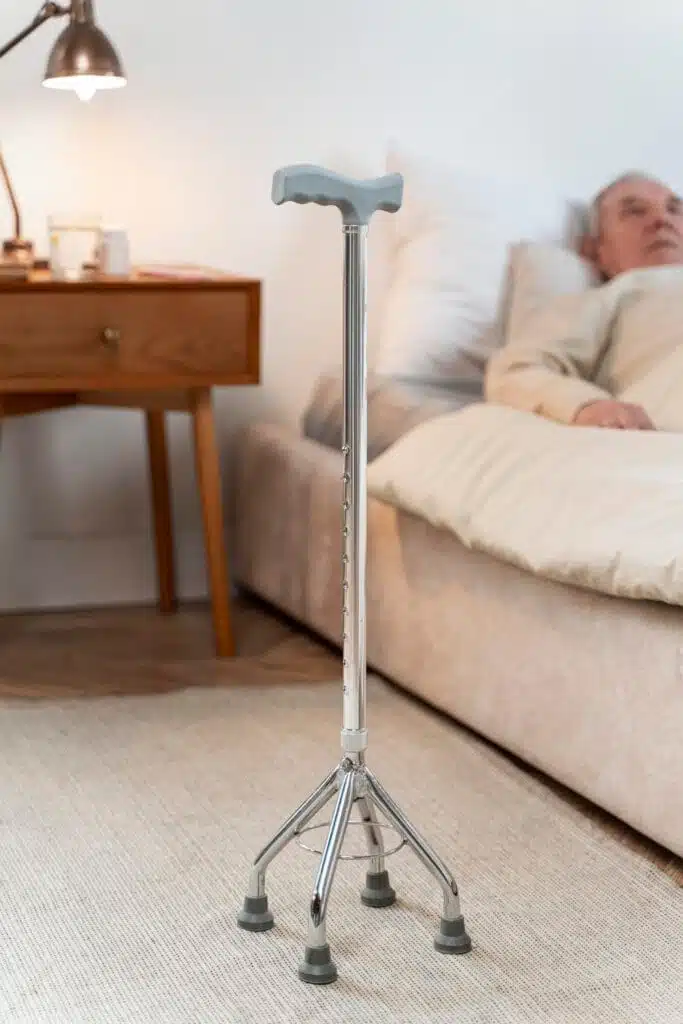 Canne quadripode noire posée contre un mur, utilisée comme aide à la marche pour les personnes à mobilité réduite.